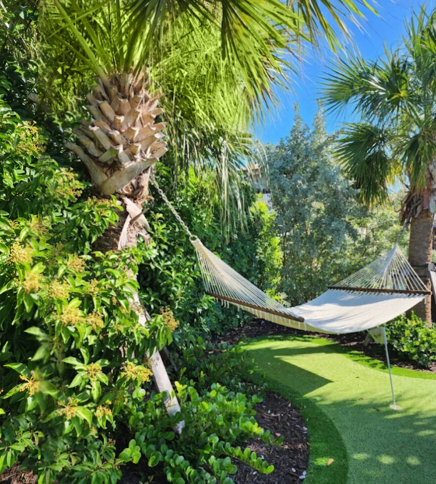 A hammock is hanging in the middle of a lush green park.